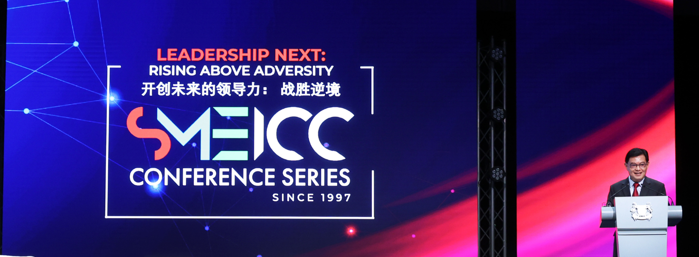 SMEICC conference stage with speaker at podium and "Leadership Next" text.